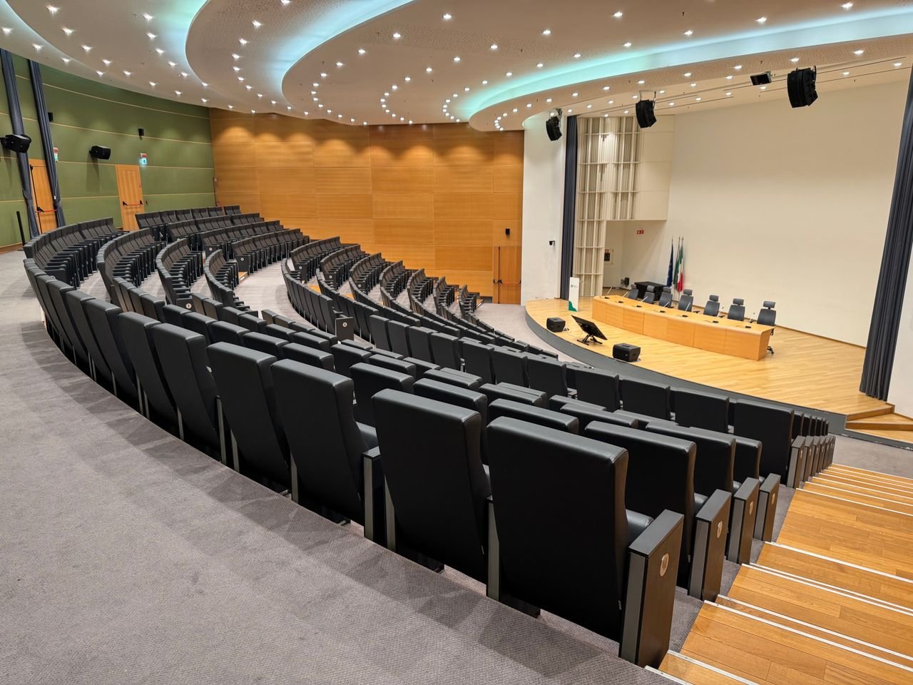 Spacious empty auditorium with rows of black seats and stage in Milano, Italy.